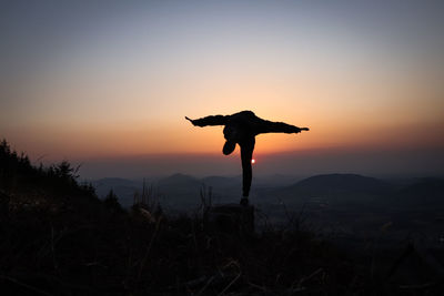 Silhouette man standing on mountain against sky during sunset