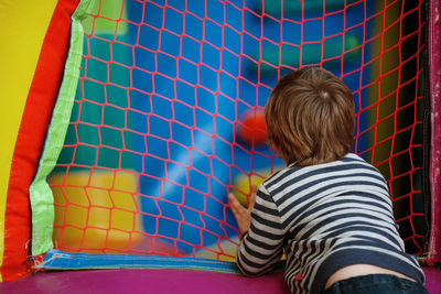 Boy standing by net at indoors playground