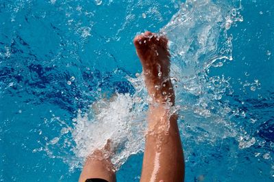 Low section of woman splashing water in swimming pool