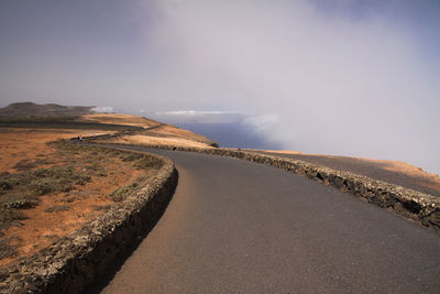 Road amidst land against sky