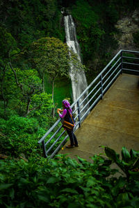 Young woman sitting on steps by waterfall in forest