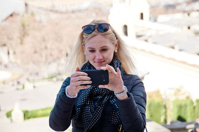 Young woman using mobile phone while standing outdoors