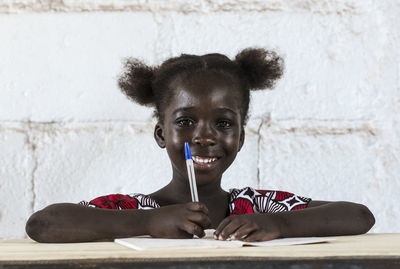Portrait of smiling girl sitting against wall