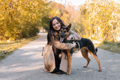 Young woman with dog on road during autumn