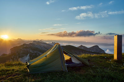 Tent on field against sky during sunset