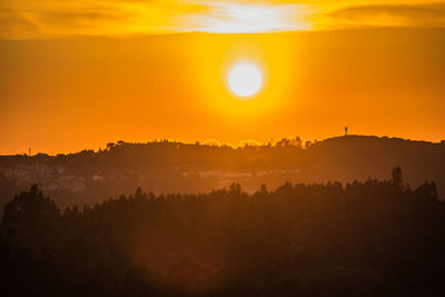 Scenic view of silhouette landscape against orange sky