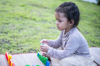 Young woman using mobile phone while sitting on field