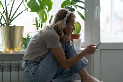 Woman listening music over mobile phone at home