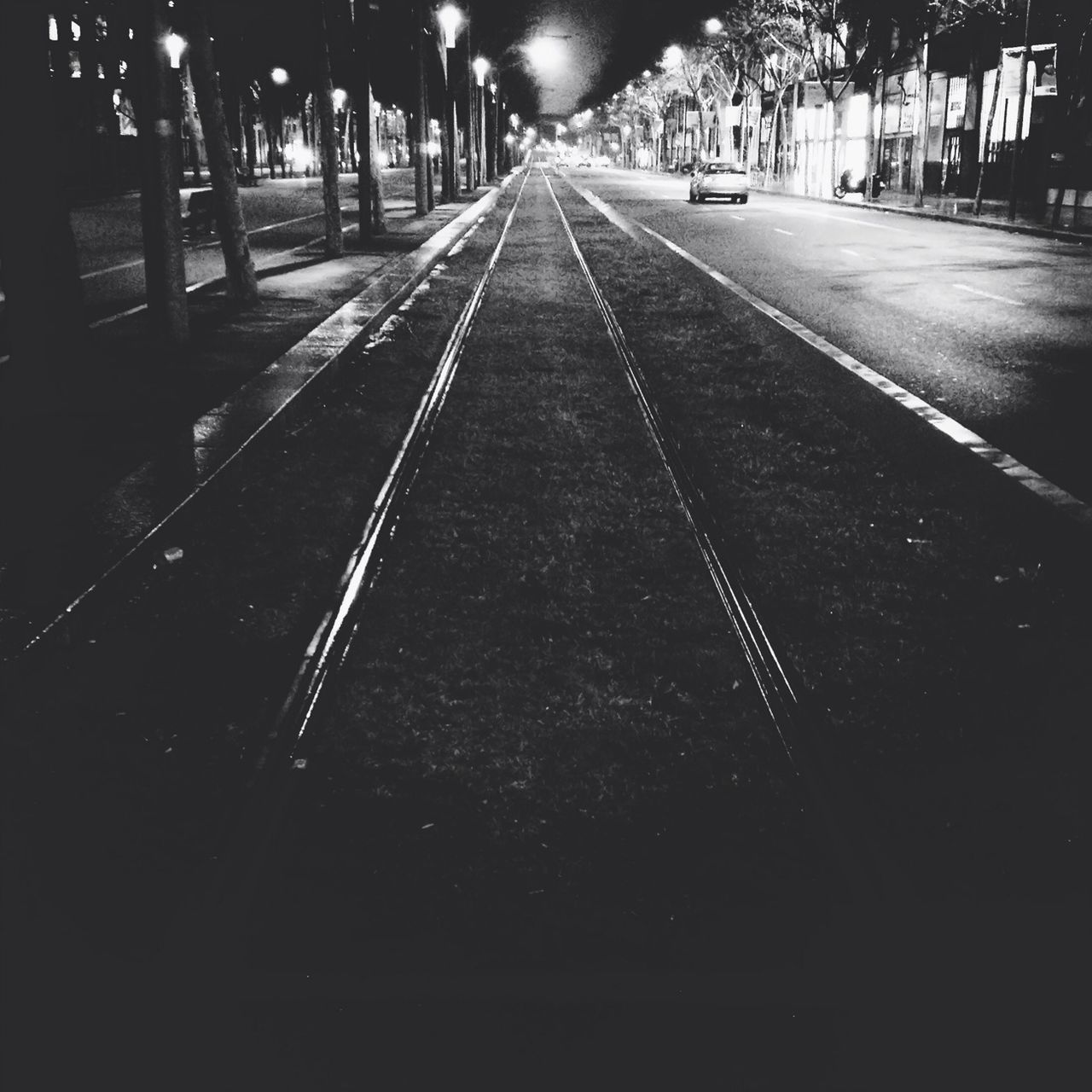 night, the way forward, transportation, illuminated, diminishing perspective, vanishing point, road, street, road marking, empty, city, street light, outdoors, asphalt, no people, incidental people, surface level, railroad track, built structure, in a row