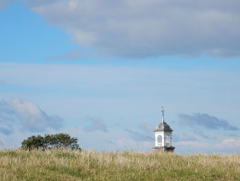 View of lighthouse on grassy landscape against sky