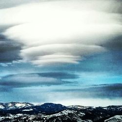 Scenic view of snow covered mountains against cloudy sky