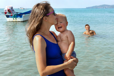 Mother holding son near sea at beach