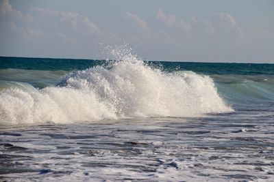 Waves splashing on sea against sky