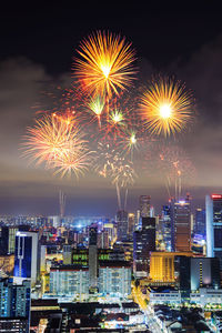 Firework display in city against sky at night