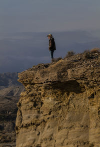 Adult man in cowboy hat standing on top of cliff in tabernas desert, almeria, spain