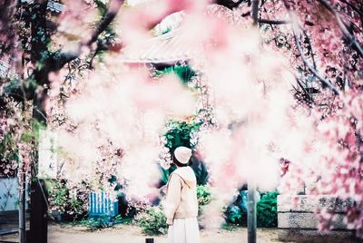 Full length portrait of young woman standing against plants