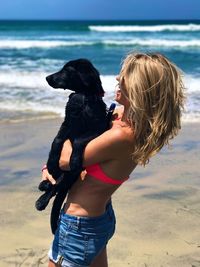 Woman with puppy standing on beach