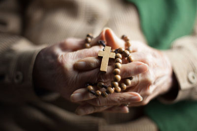 Close-up of woman holding rosary with hands clasped