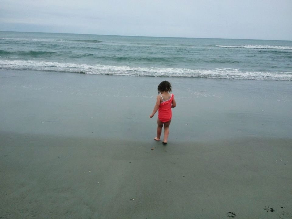 REAR VIEW OF GIRL WALKING ON BEACH