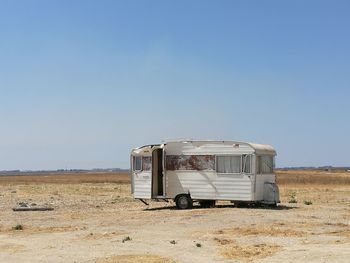 Abandoned motor home on field against clear sky
