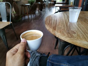 Hand holding coffee mug with glass of water.