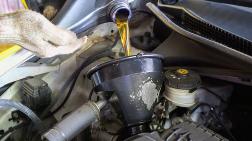 Mechanic pouring oil in car engine