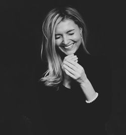 Portrait of smiling young woman against black background