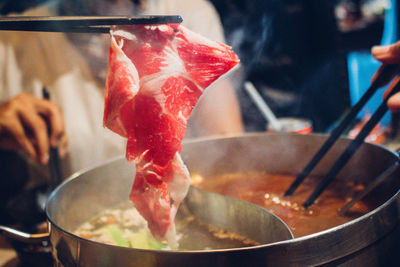 Cropped hands of people using chopsticks while preparing food