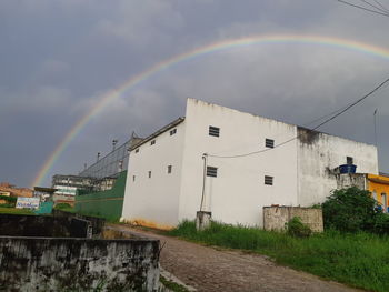 Low angle view of rainbow over buildings against sky