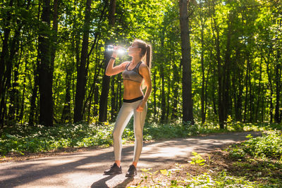 Woman standing by tree trunks in forest