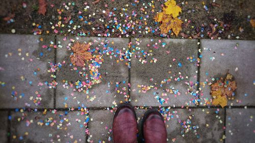 Low section of person standing by multi colored shoes