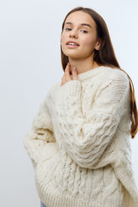 Portrait of young woman standing against white background