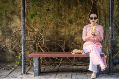 Woman with vietnam culture traditional dress sit and eating banh mi at ancient town hoi an.