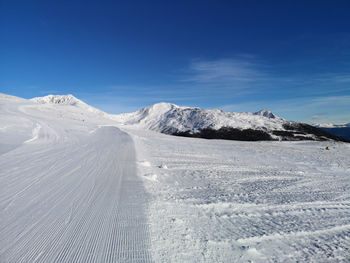 Scenic view of snowcapped mountains against blue sky