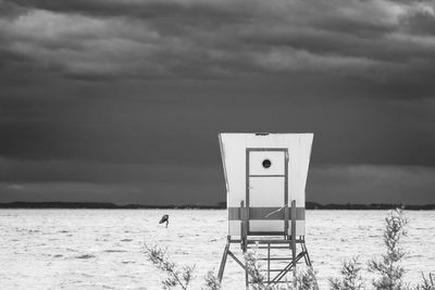 Lifeguard hut on beach against cloudy sky