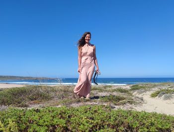 Portrait of young woman on beach against clear sky