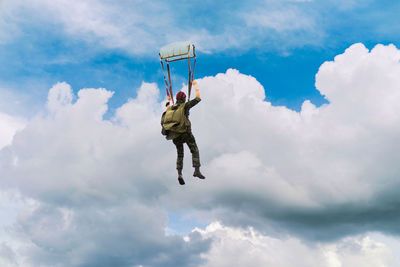 Low angle view of man paragliding against sky