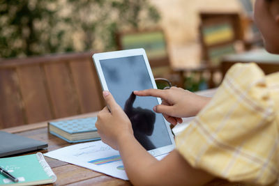 Midsection of woman using mobile phone on table