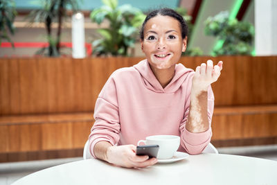 Portrait of smiling woman sitting on table