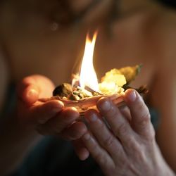 Close-up of hand holding burning candles