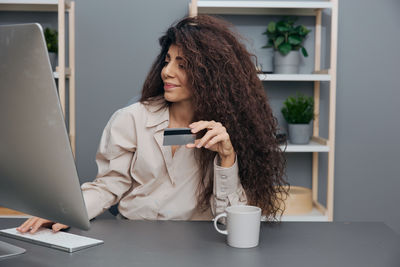 Young woman using mobile phone at table