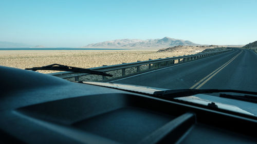 Road by mountain seen through car windshield