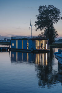 Illuminated houseboat with reflection on yser river at sunset