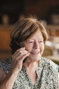 Senior woman smiling while talking on mobile phone at cafe