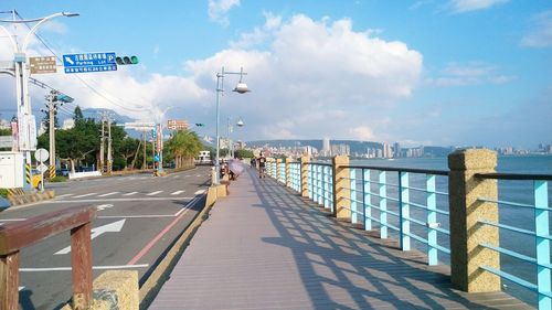 Shadow on promenade in city against cloudy sky