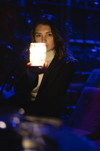 Portrait of beautiful woman showing glowing jar at night