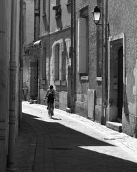 Rear view of man walking on street amidst buildings