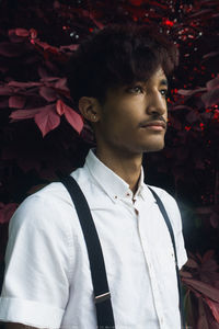 Portrait of young man standing against tree at night
