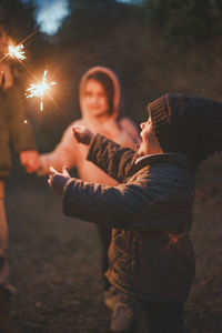 Rear view of people holding sparkler at night