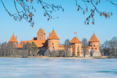 Medieval castle of trakai, vilnius, lithuania in winter with frozen lake and ukrainian flag